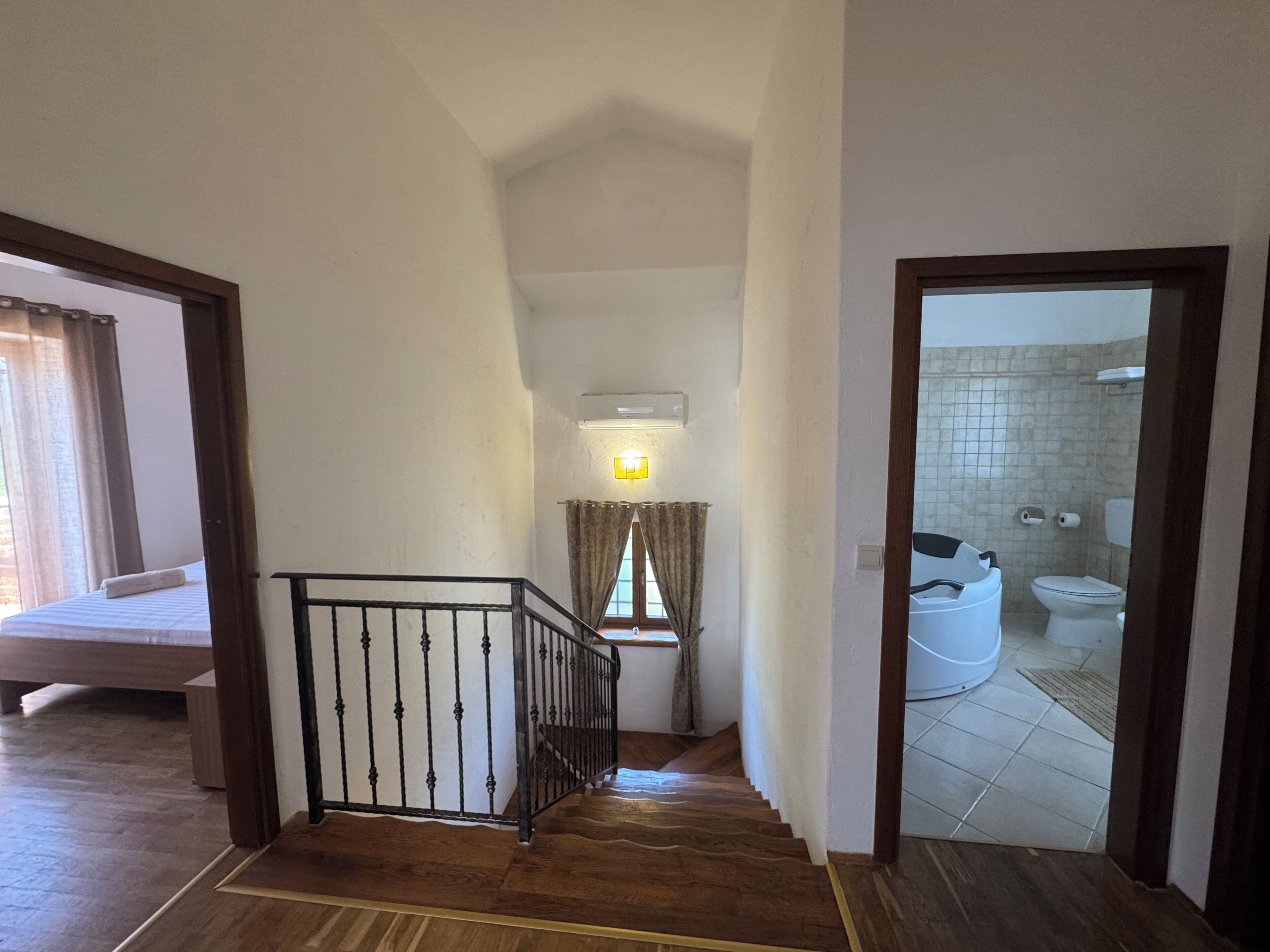A staircase leading to a bedroom with a bed and a bathroom visible in the background.