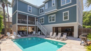 A two-story house with a swimming pool, outdoor seating, and a covered patio area. - Walk to beach-8BR w/ private pool-Sleeps 24-Ideal for groups and multi-families (Hilton Head Island)