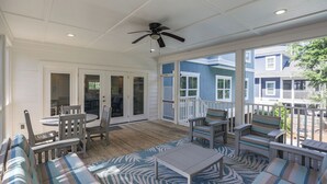 A covered patio with a ceiling fan, wooden deck, and outdoor seating. - Walk to beach-8BR w/ private pool-Sleeps 24-Ideal for groups and multi-families (Hilton Head Island)