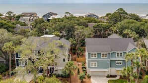 A residential area with houses surrounded by trees and a view of the ocean. - Walk to beach-8BR w/ private pool-Sleeps 24-Ideal for groups and multi-families (Hilton Head Island)