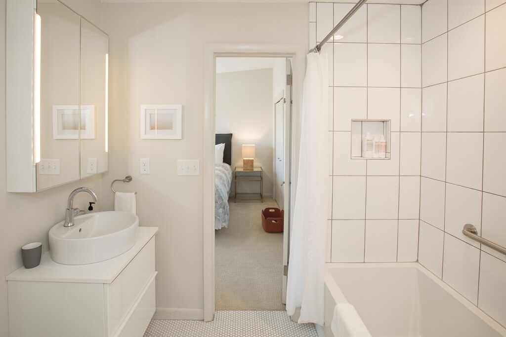 Une salle de bain moderne avec un lavabo, un miroir et un espace douche.
