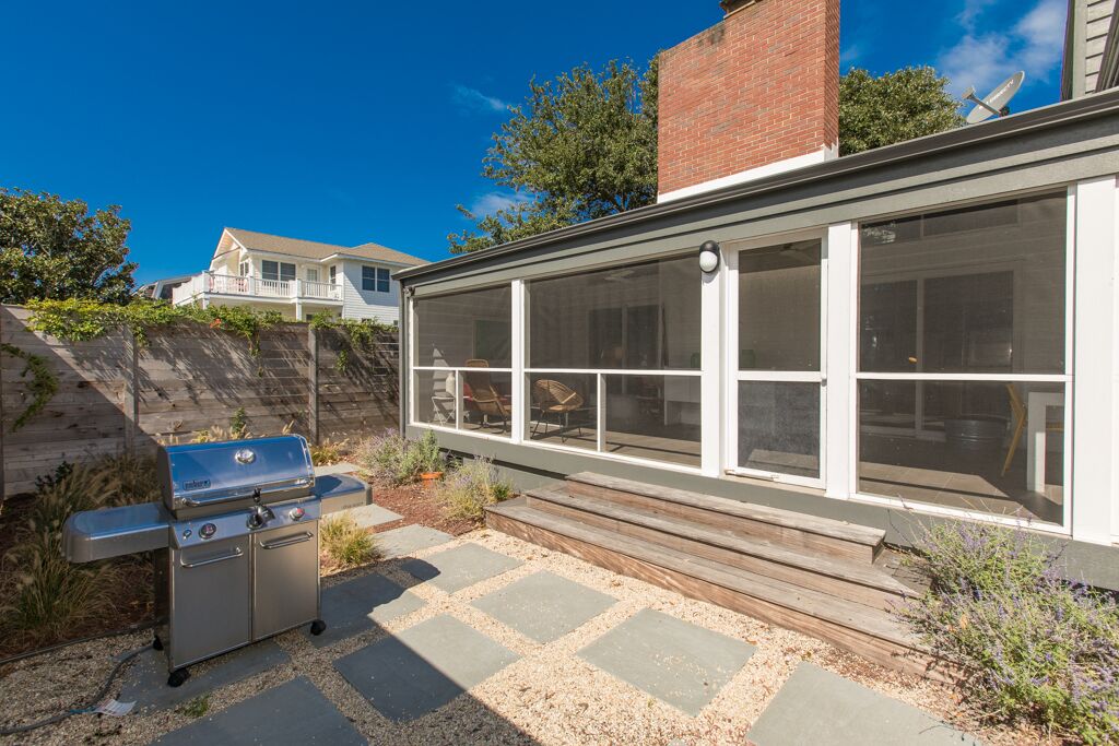 Una casa moderna con un'ampia stanza finestrata, un barbecue e un vialetto in pietra.