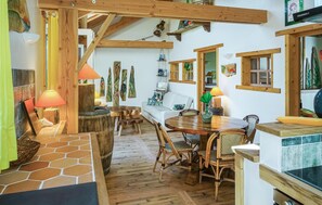 Un intérieur chaleureux et rustique, avec une table à manger en bois, des chaises en osier et un sol carrelé en pierre.