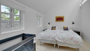 Un dormitorio con dos camas, una ventana, un cuadro y un escritorio con una lámpara.