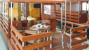 A wooden deck with tables and chairs, a small table with a few items, and a ladder.