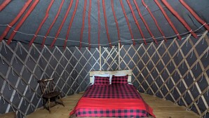 A yurt with a bed, wooden floor, and a lattice wall. - Escape to Nature: Cozy Yurt on a Heritage Farm with Trails, Pond, & Sauna (Powassan)