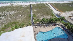 Un resort frente al mar con piscina, sombrillas de playa y un muelle largo.