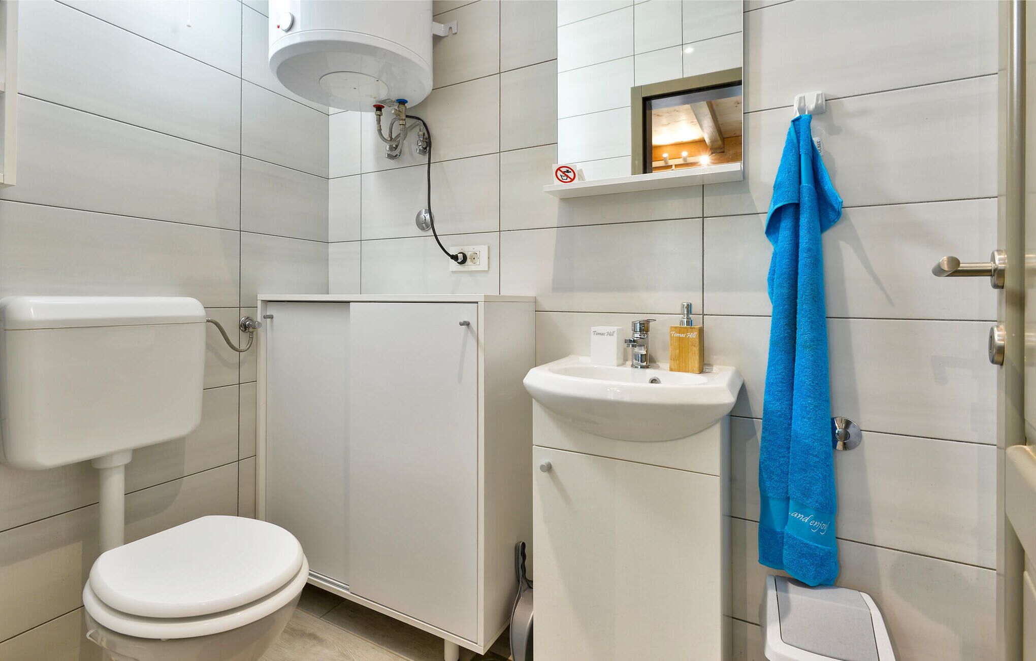 Une salle de bain avec des toilettes, un meuble, un lavabo et une serviette accrochée au mur.