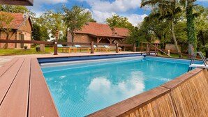Ein Schwimmbecken mit Holzterrasse, Liegestühlen und einem Holzzaun.