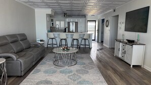 A modern living room with a grey sofa, a round coffee table, and a patterned rug. - Beautiful Views Just Steps to the gulf! (Fort Myers)