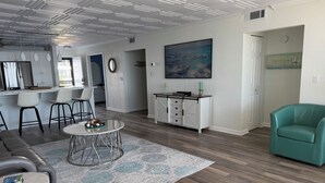A modern living room with a dining area, a kitchen, and a hallway. - Beautiful Views Just Steps to the gulf! (Fort Myers)
