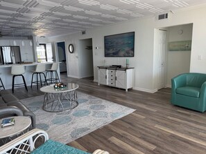 A modern living room with a dining area, a kitchen, and a hallway. - Beautiful Views Just Steps to the gulf! (Fort Myers)