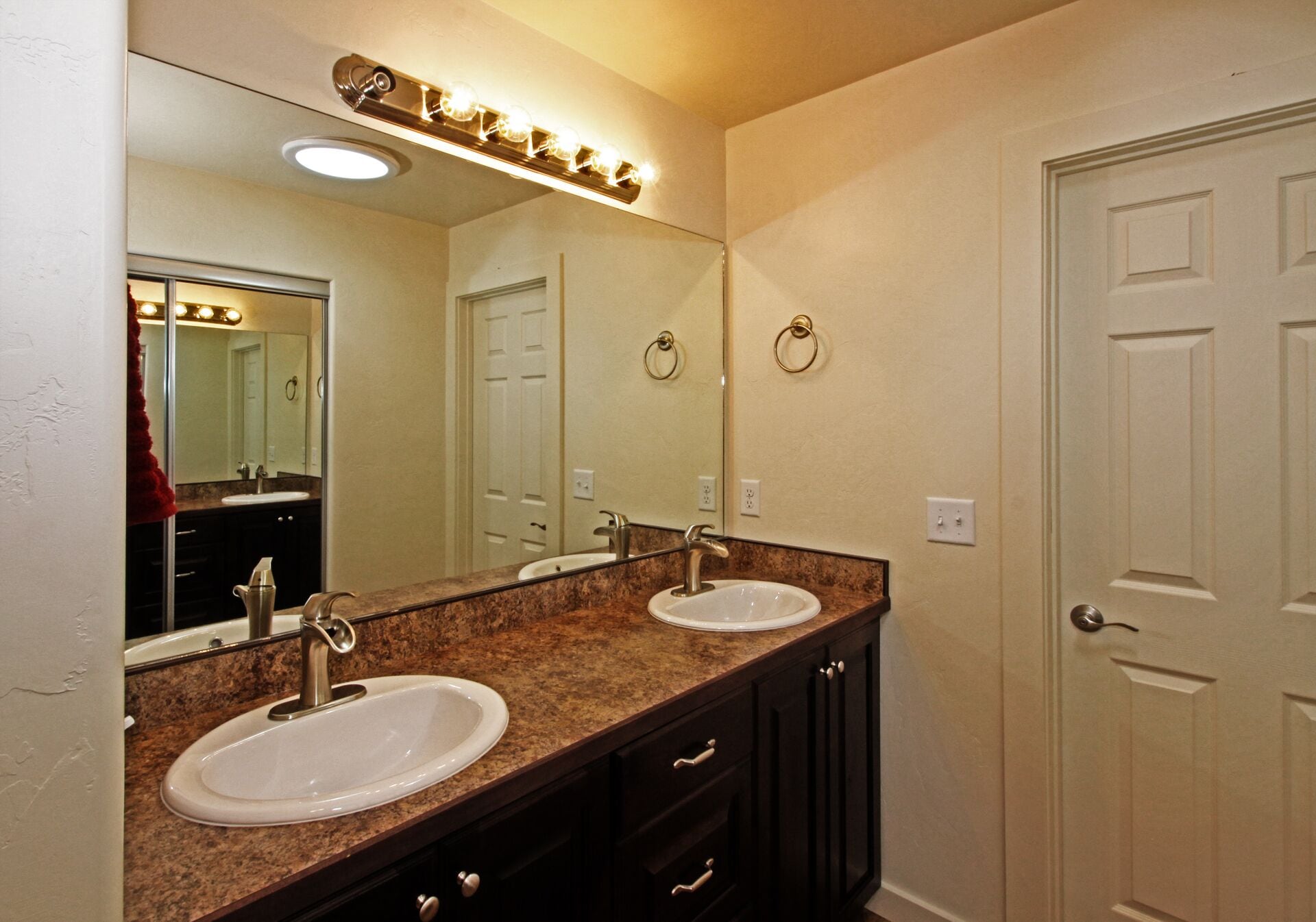 A bathroom with two sinks, a large mirror, and a vanity with drawers.