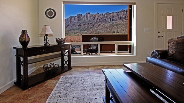 A living room with a large window offering a view of a rocky landscape. - Beautiful Townhome adjacent to the Pool and Hotub (Moab)