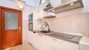 Een moderne keuken met witte kasten, een roestvrijstalen afzuigkap en een inbouwoven.