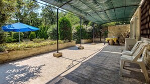 An outdoor patio area with a covered seating area, stone flooring, and surrounding greenery. - 2 bedroom stunning home in Salernes (Salernes)
