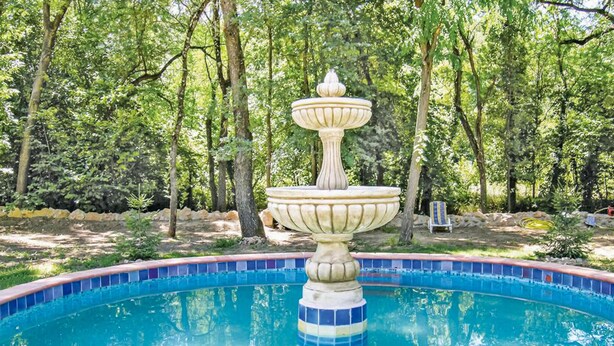A swimming pool with a decorative fountain in the center surrounded by trees. - 2 bedroom stunning home in Salernes (Salernes)