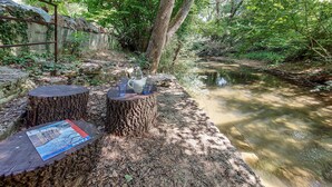 A serene outdoor setting with a wooden table and chairs by a calm stream, surrounded by lush greenery. - 2 bedroom stunning home in Salernes (Salernes)