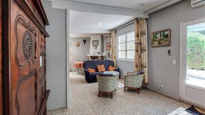A living room with a sofa, two armchairs, a dining table with chairs, a fireplace, and a large window with curtains. - 2 bedroom stunning home in Salernes (Salernes)