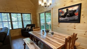 Ein Holzhütten-Interieur mit Esstisch, Bänken, einer Couch und einem Bärenbild.