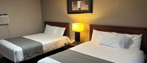A hotel room with two single beds, a bedside lamp, a framed picture on the wall, and a ceiling light.