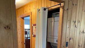 Un interno in legno con angolo lavanderia, comprensivo di lavatrice e stendibiancheria.
