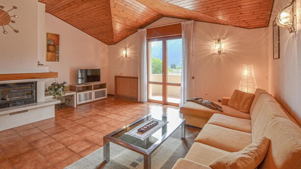 A spacious living room with a fireplace, a television, and a large window providing a view of the outdoors.