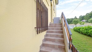 A set of outdoor stairs leading up to a building with a yellow wall and a metal fence.