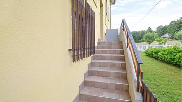 Eine Treppe führt nach oben zu einem Gebäude mit einer gelben Wand und einem Metallzaun.