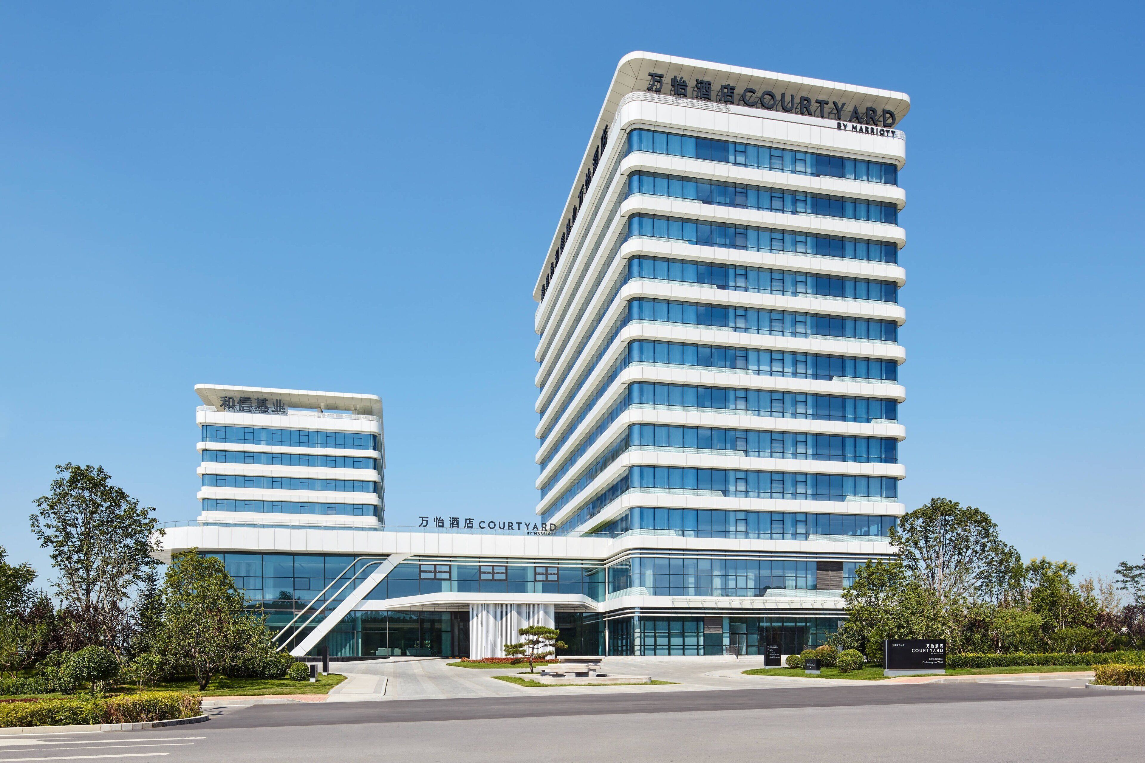 A modern hotel with a curved facade, multiple floors, and a prominent entrance with a glass canopy.