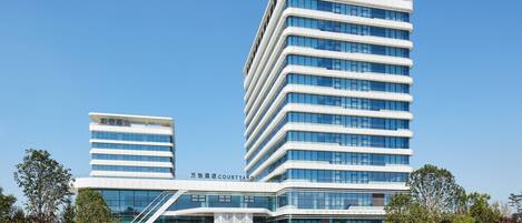 A modern hotel with a curved facade, multiple floors, and a prominent entrance with a glass canopy.