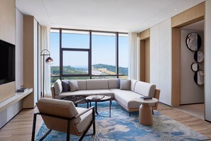 A modern living room with a large sectional sofa, a coffee table, and a TV mounted on the wall. - Courtyard by Marriott Qinhuangdao (Qinhuangdao)