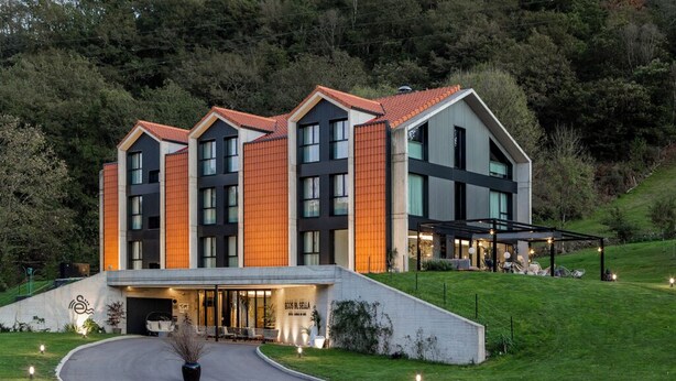 Un hotel moderno con una entrada curva, un área de estar al aire libre cubierta y un cartel que dice "Hotel del Sol".