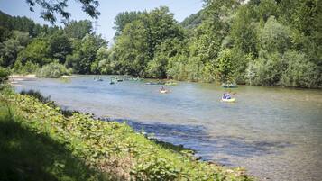 A river with multiple kayaks and canoes, surrounded by lush greenery and trees.