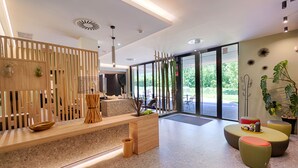Un área de recepción moderna con un mostrador de madera, zona de estar y ventanas amplias que ofrecen vistas al exterior.