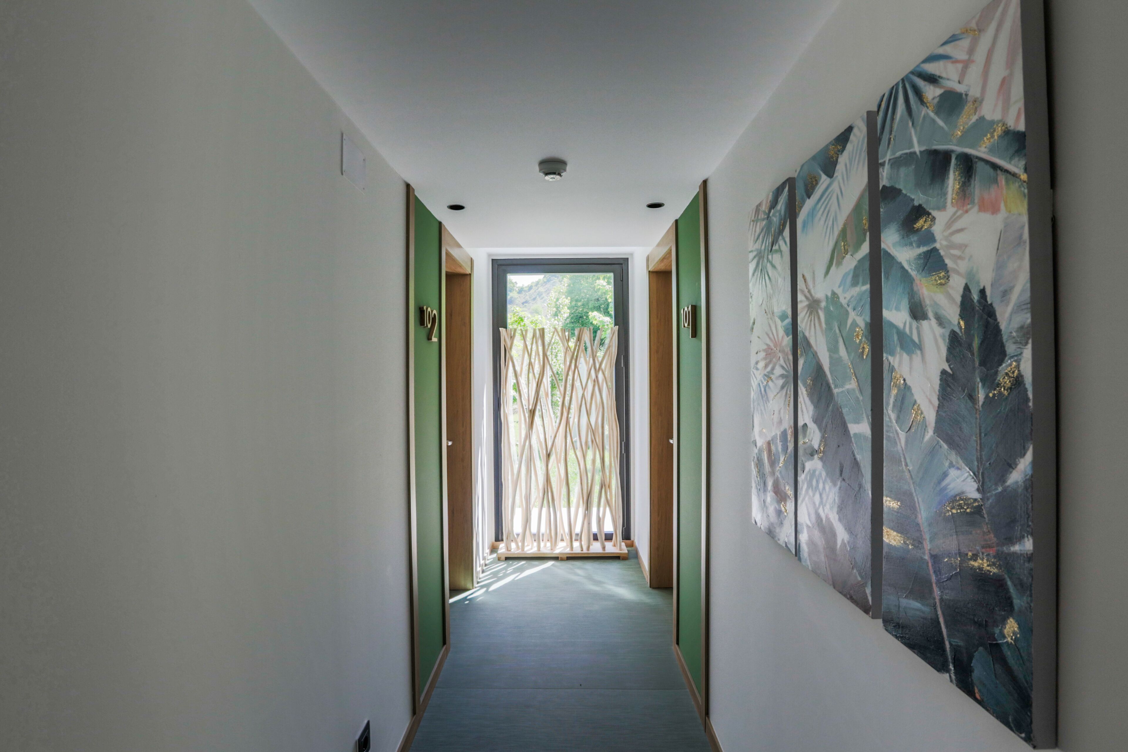 Ein Flur mit Blick auf einen Balkon, einer Holzwand und einem großen abstrakten Gemälde an der Wand.