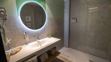 A modern bathroom with a large mirror, a sink, and a shower.