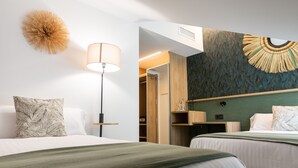 Habitación de hotel con dos camas, una lámpara de pie, un adorno en la pared y un armario.