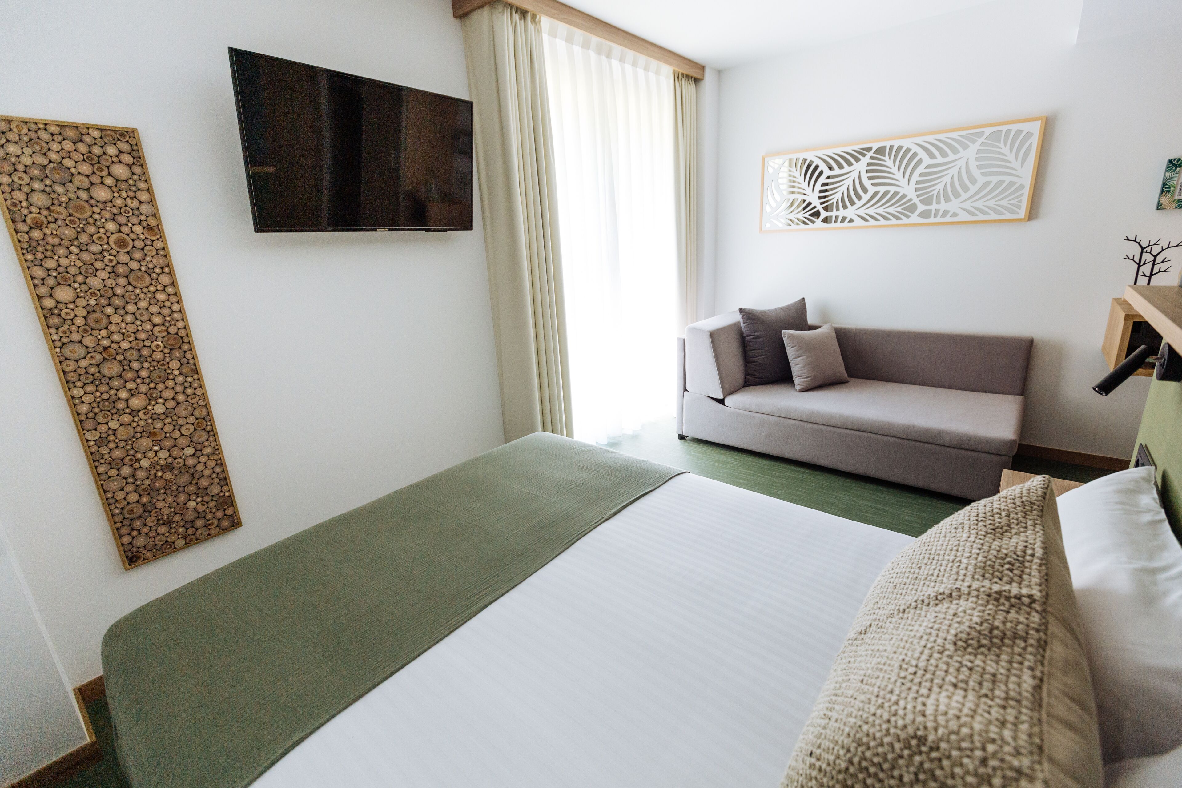 Une chambre d’hôtel comprenant un lit, un canapé, une télévision et un élément décoratif mural.