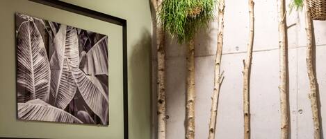 Una habitación con una mesa y sillas, un cuadro en la pared y una planta colgando del techo.