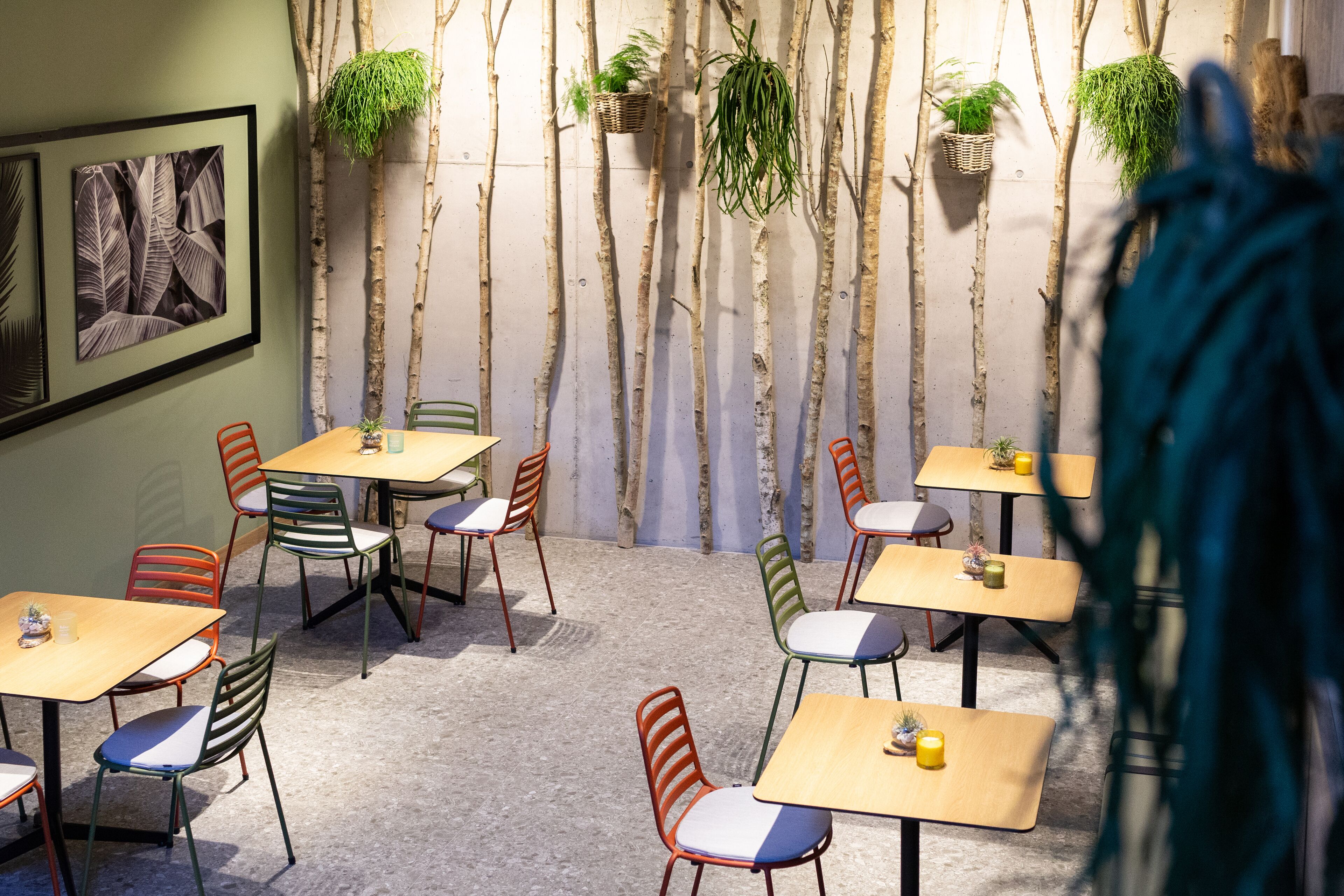 A dining area with multiple tables and chairs, some with plants on them.