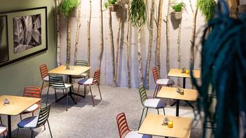 A dining area with multiple tables and chairs, some with plants on them.