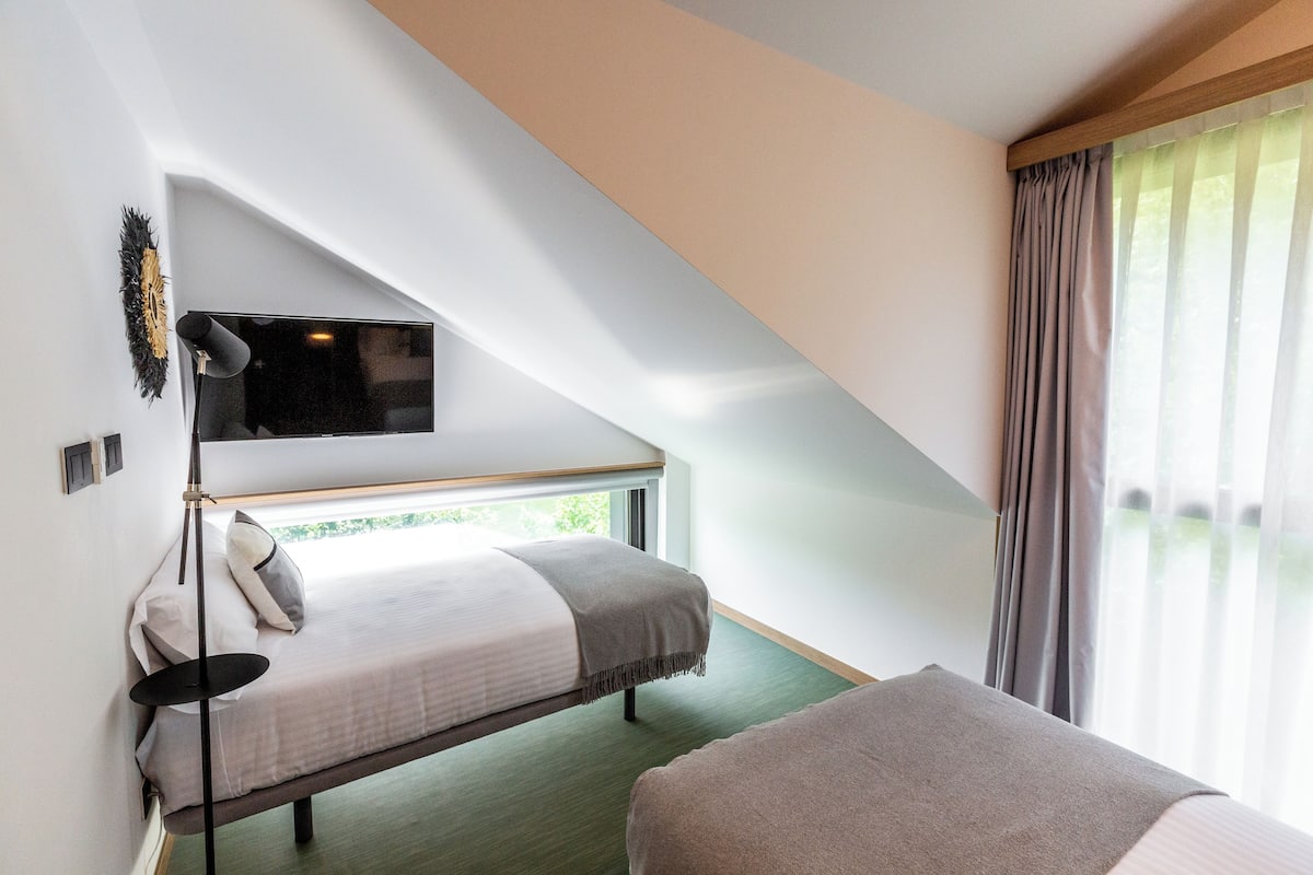 Um quarto com uma cama beliche, uma televisão de tela plana na parede e uma janela com cortinas.