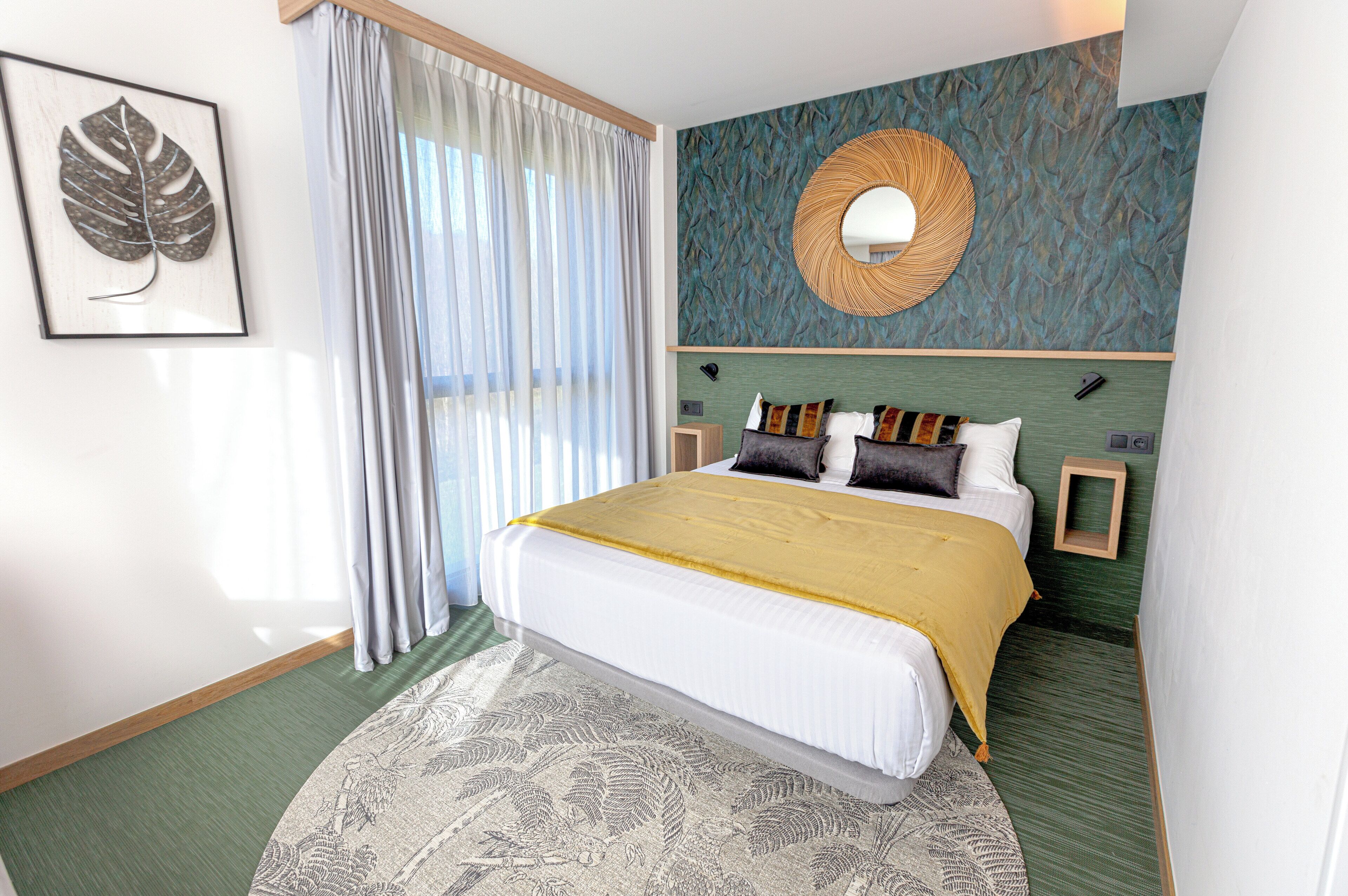 Un dormitorio ordenado con una cama grande, un espejo en la pared y una obra de arte con una hoja enmarcada.