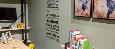 Una habitación con una mesa de madera, una silla amarilla, una estantería con libros y una pared con una cita motivacional.