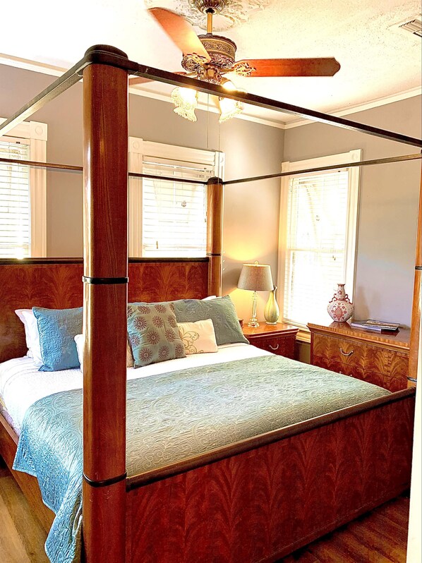 A four-poster bed with a wooden frame and a ceiling fan above.