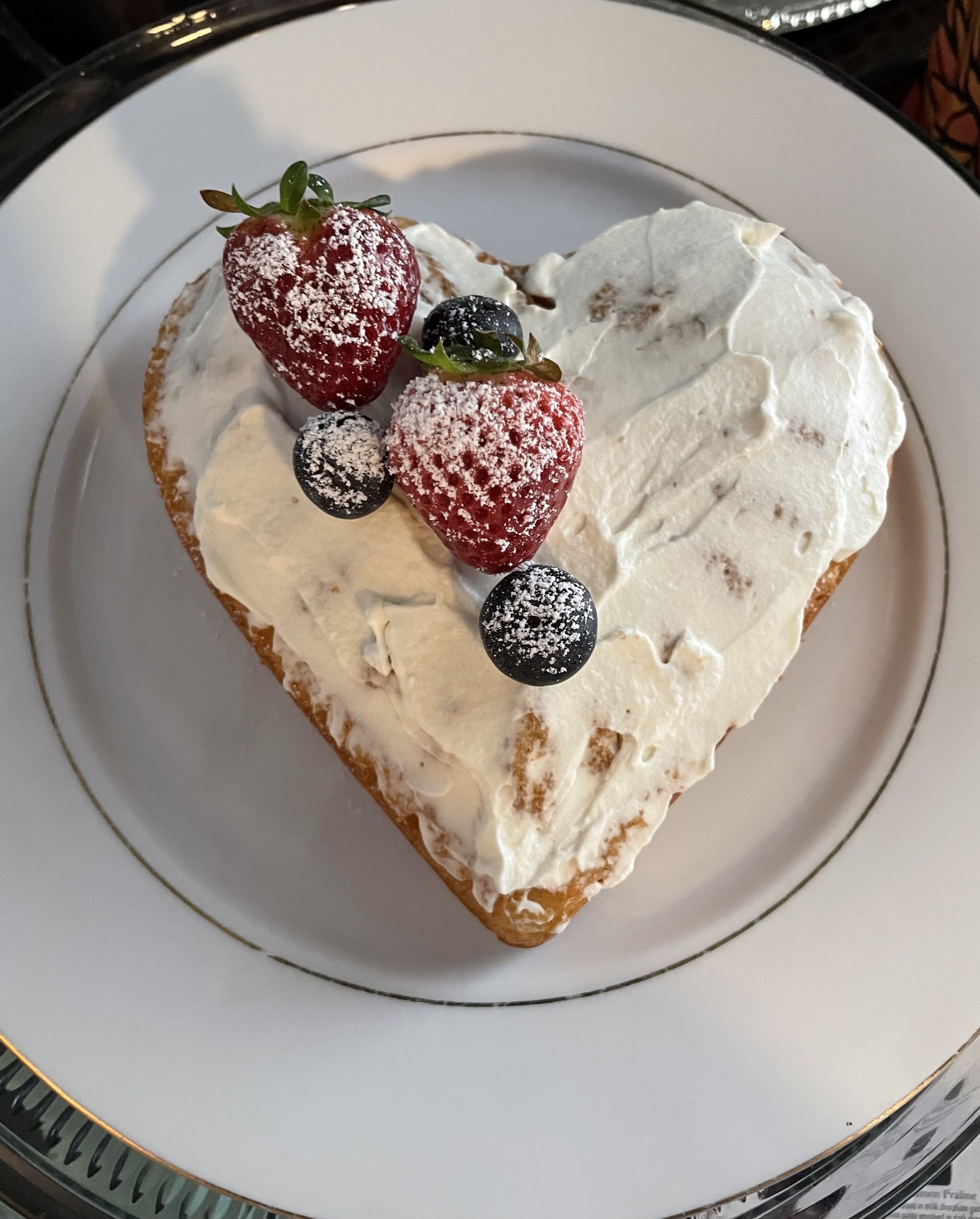 Un dessert servi dans une assiette, accompagné de crème fouettée et de fraises.