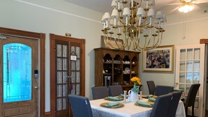 A dining area with a chandelier, a wooden cabinet with glass doors, and a dining table set for six. - Peace & Plenty Inn Bed & Breakfast (St. Augustine)