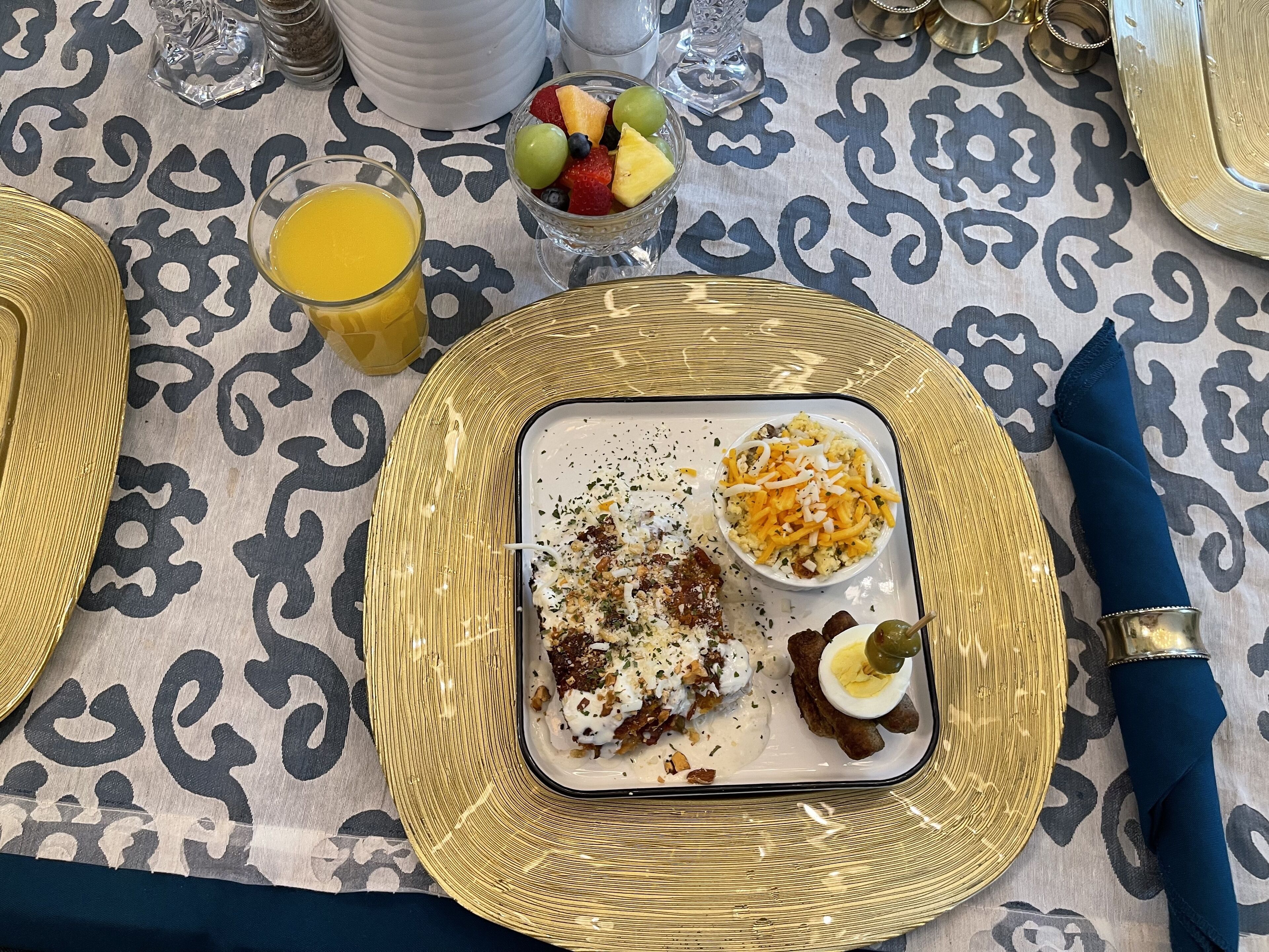 A table set with a meal, including a bowl of salad, a plate of food, and a glass of orange juice.
