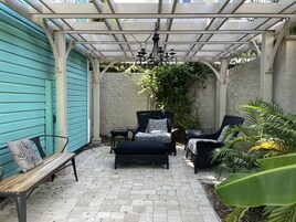Un patio cubierto con mobiliario de mimbre, un banco y una lámpara colgante.